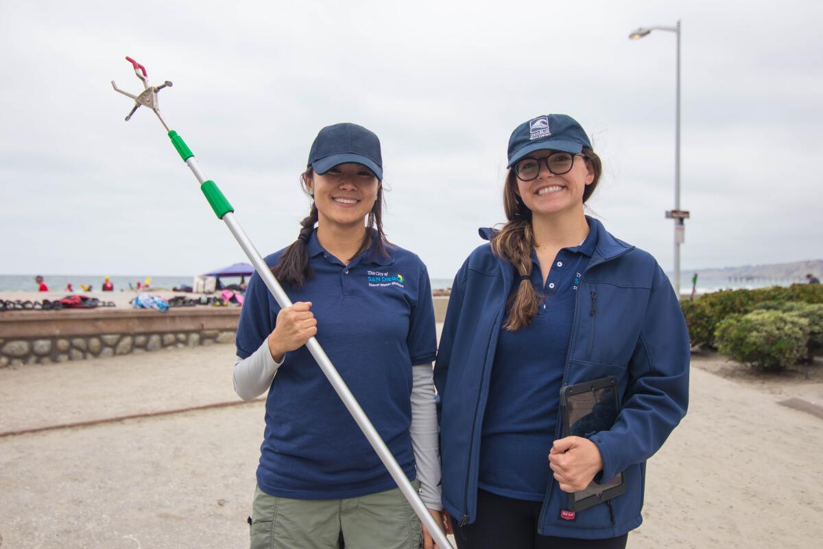 Two women wearing navy blue hats and polos with the city of San Diego logo on the shirts.