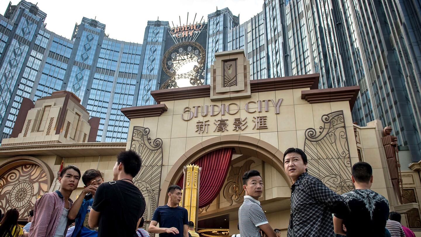 People wait outside the Hollywood-themed Studio City casino-resort ahead of its opening Tuesday in Macau, which is trying to bounce back from a precipitous drop in gambling revenue.