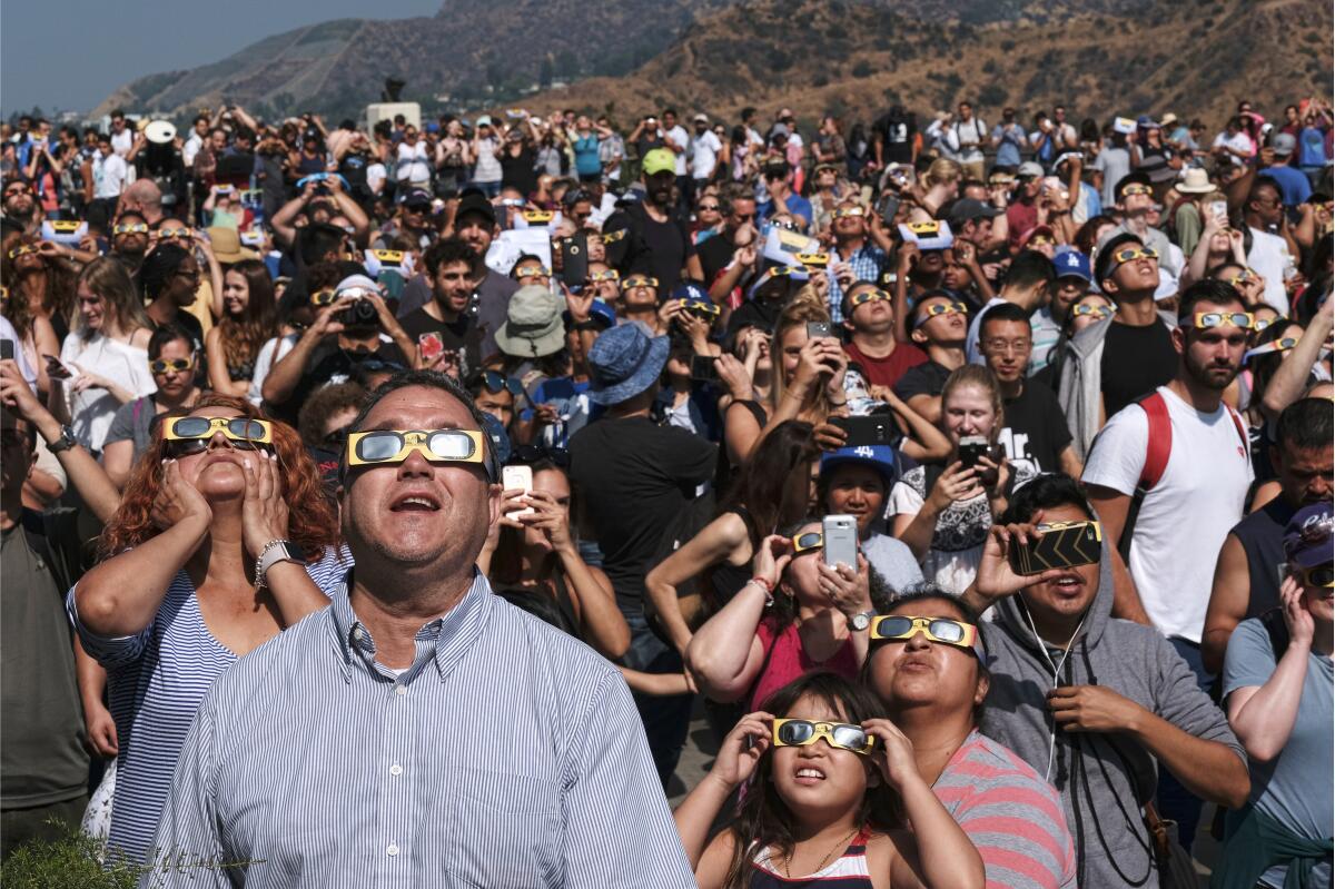 People wearing protective eye glasses watch a solar eclipse at Griffith Observatory in 2017. 