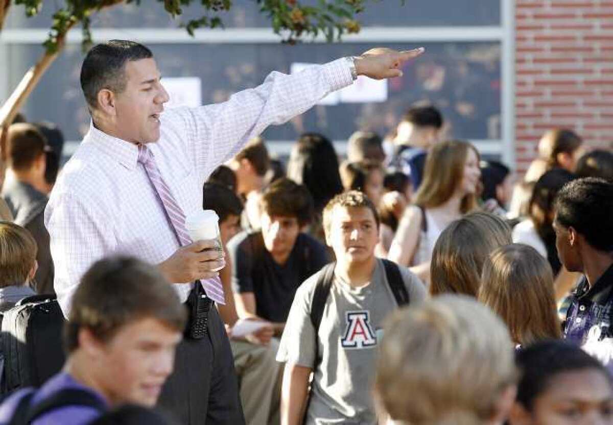 John Burroughs High School Principal John Paramo helps guide students to classrooms while standing on the bench of a picnic table on the first day of school.