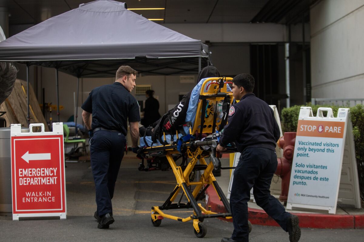Two paramedics with a patient on a gurney enter a hospital.