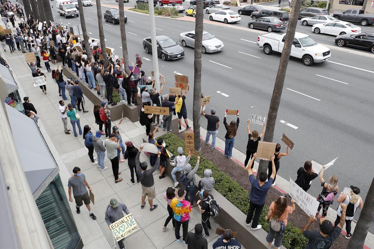 Demonstrators rally during a peaceful protest against police brutality at Triangle Square on Friday in Costa Mesa.