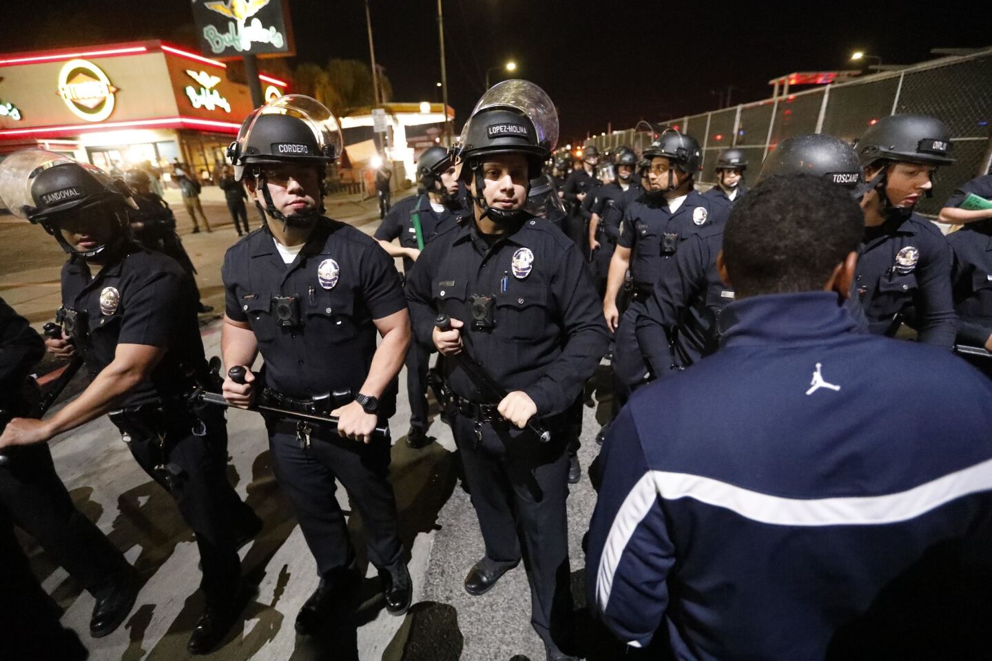 L.A. police push back a crowd along Crenshaw Boulevard after a stamped erupted, injuring several people, during a vigil Monday for slain rapper Nipsey Hussle.