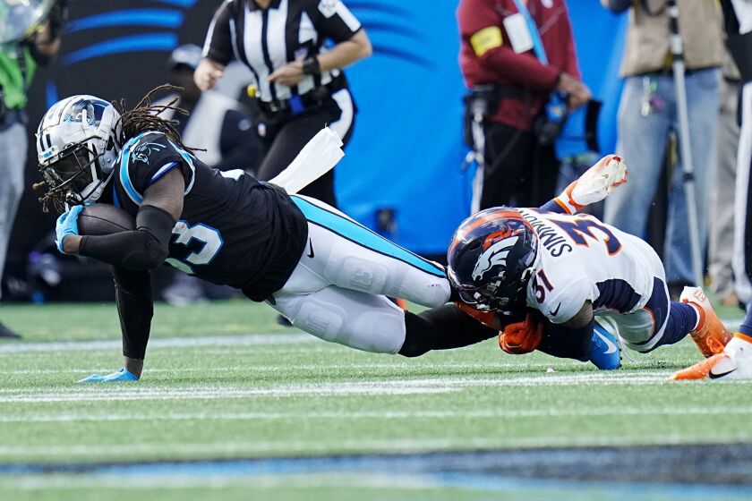 Carolina Panthers running back D'Onta Foreman is tackled by Denver Broncos safety Justin Simmons during the first half of an NFL football game between the Carolina Panthers and the Denver Broncos on Sunday, Nov. 27, 2022, in Charlotte, N.C. (AP Photo/Rusty Jones)