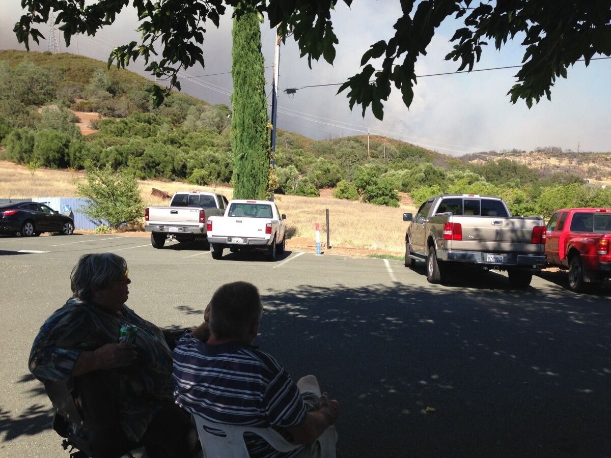 Cheryl and Chris Christian, who live in Clearlake Oaks, Calif., watch the smoke billowing from their neighborhood on Monday afternoon. The Rocky fire has forced thousands of evacuations.