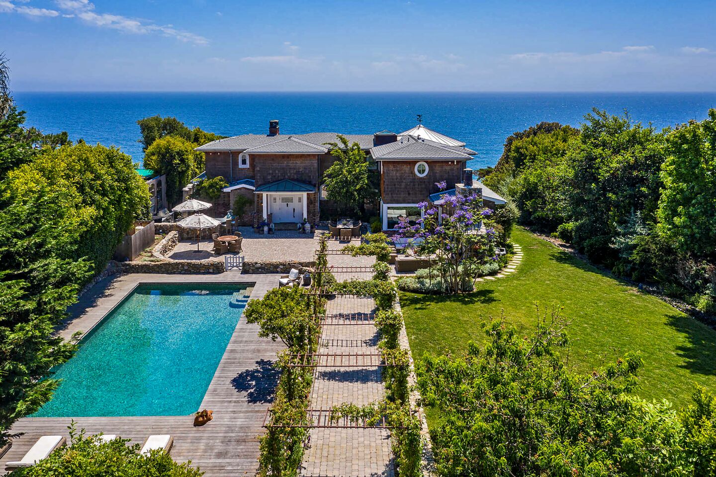 This coastal Cape Cod overlooks the ocean from a bluff in Point Dume, descending to a stretch of private beach.