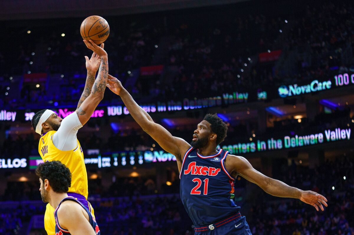 Los Angeles Lakers' Anthony Davis, left, shoots the ball with Philadelphia 76ers' Joel Embiid