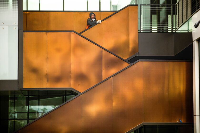 A worker cleans the railing along a staircase on the exterior of the West End office complex in West Los Angeles.
