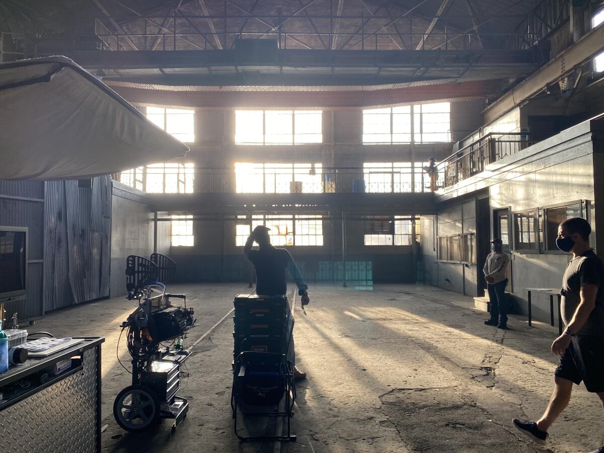 People in a mostly empty warehouse with sunlight and shadows