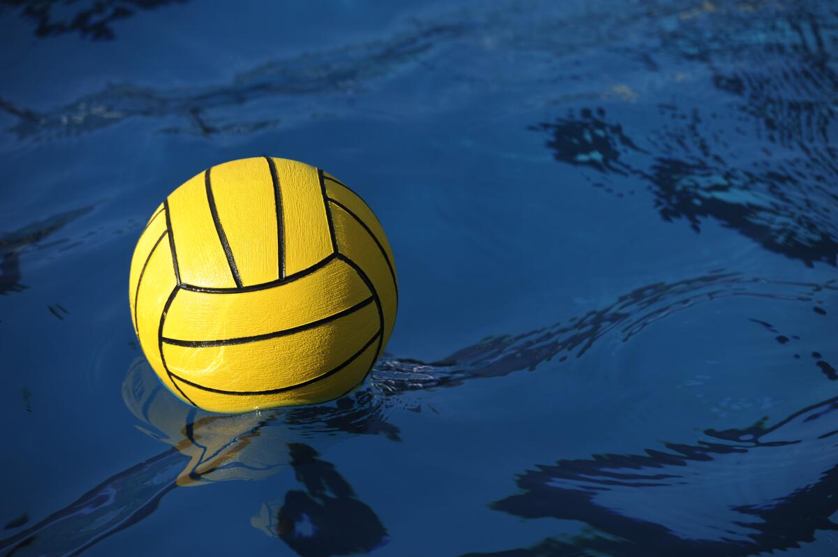 A yellow water polo ball floats in a pool.