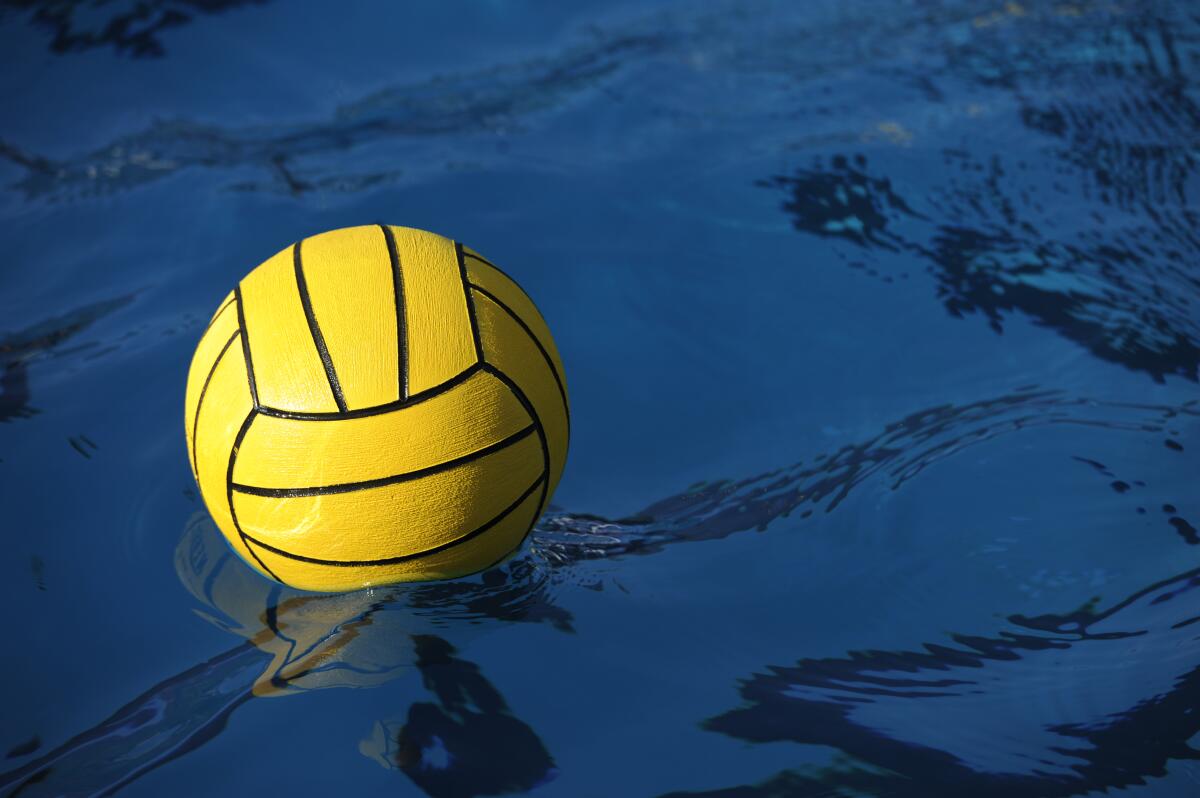 A yellow water polo balls rests in a pool.