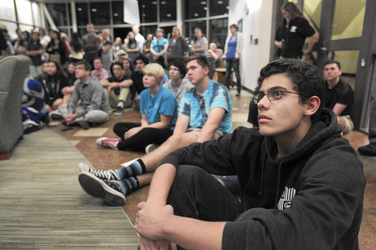 An overflow crowd of spectators fills the Poway school district office lobby as they watch the school board meeting on video monitors.