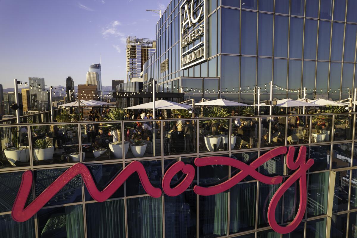 A rooftop bar with big "AC Hotels Marriot" and "Moxy" sign and strings of lights