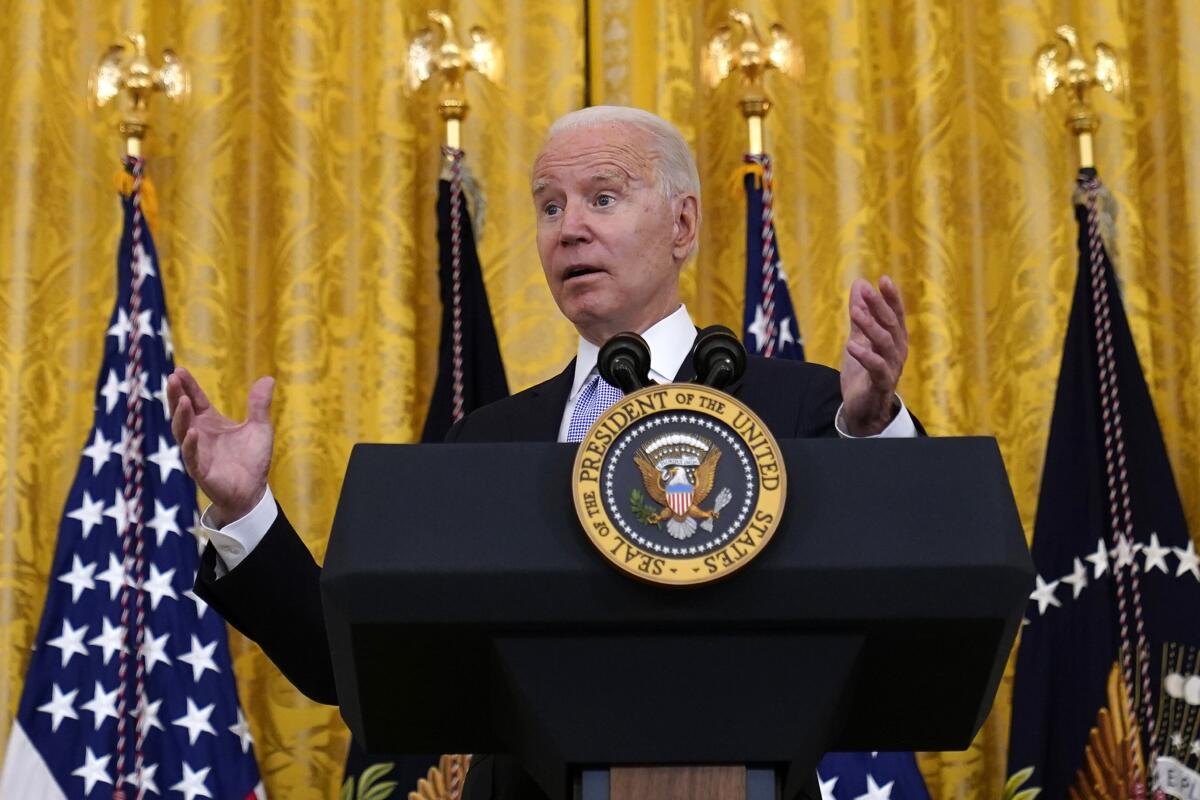 President Biden gestures as he speaks at a lectern with the presidential seal