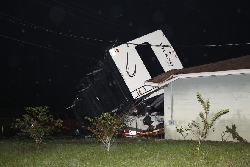 A camper rests on top of a boat trailer and the corner of a home as Tropical Storm Nestor passed the area on Saturday, Oct. 19, 2019 in Kathleen, Fla. Nestor was downgraded Saturday after it spawned a tornado that damaged several homes. (Luis Santana/Tampa Bay Times via AP)