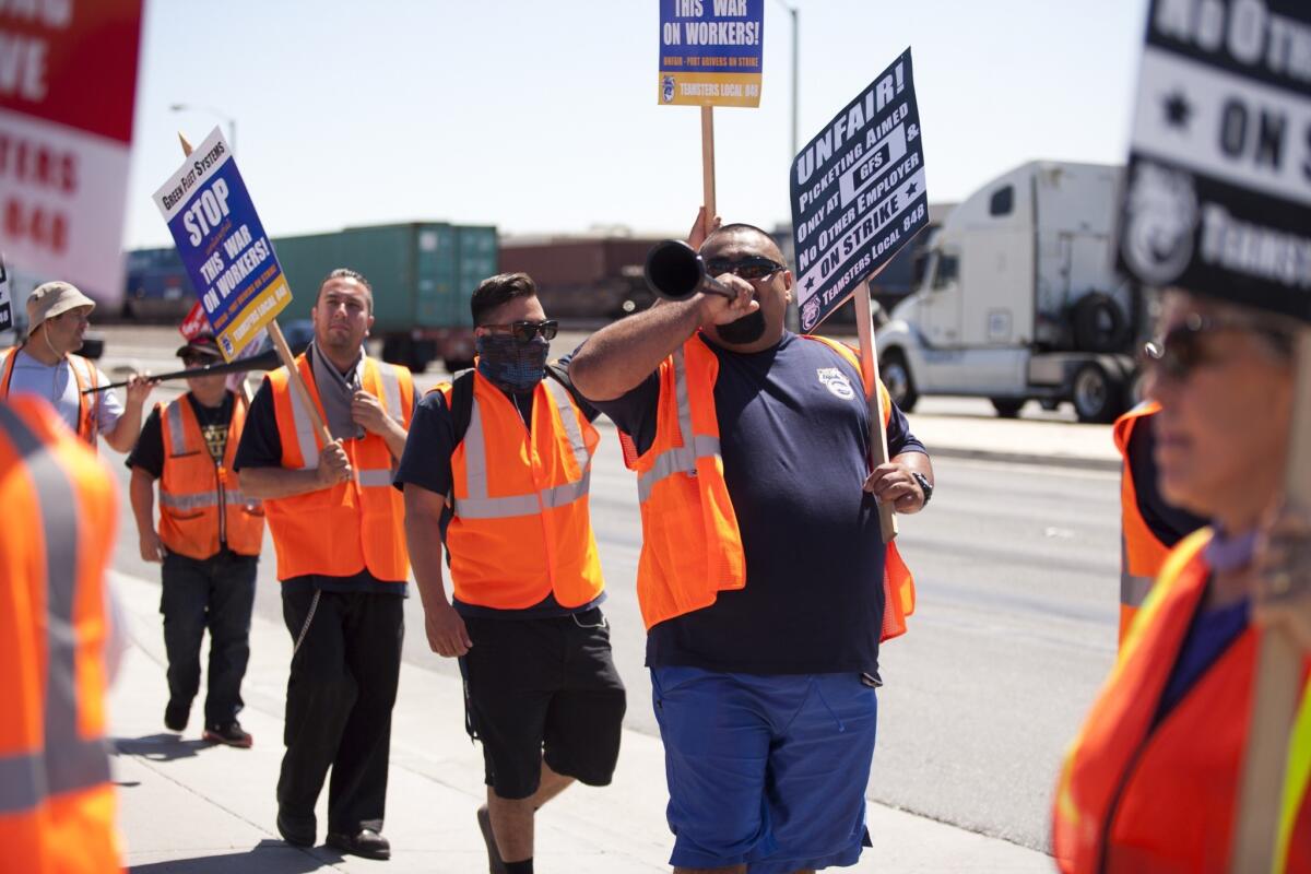 Picketers walk in front of the Green Fleet Systems building in Long Beach on Monday.