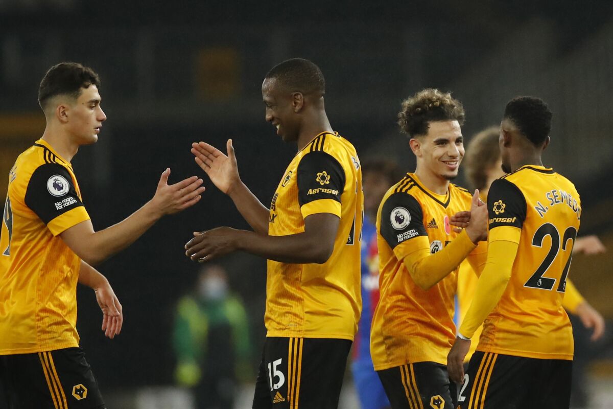 Wolverhampton Wanderers' players shake hands at the end of the English Premier League soccer match between Wolverhampton Wanderers and Crystal Palace at the Molineux Stadium in Wolverhampton, England, Friday, Oct, 30, 2020. (Andrew Boyers/Pool via AP)