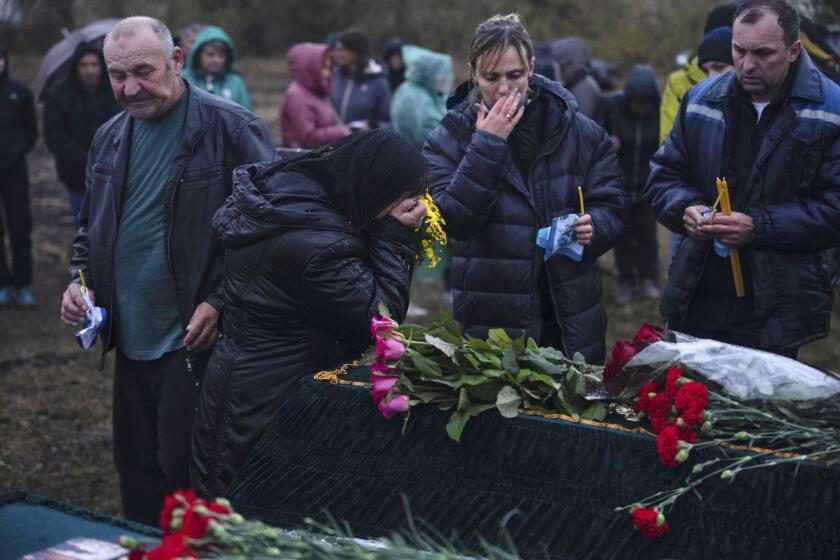 Relatives and friends mourn near the coffins of Tetiana Androsovych, 60, and Mykola Androsovych, 63, killed by a rocket strike, at a graveyard in the village of Hroza, near Kharkiv, Ukraine, Saturday, Oct. 7, 2023. The Ukrainian village of Hroza has been plunged into mourning by a Russian rocket strike on a village store and cafe that killed more than 50 people on Thursday, Oct. 5. (AP Photo/Alex Babenko)