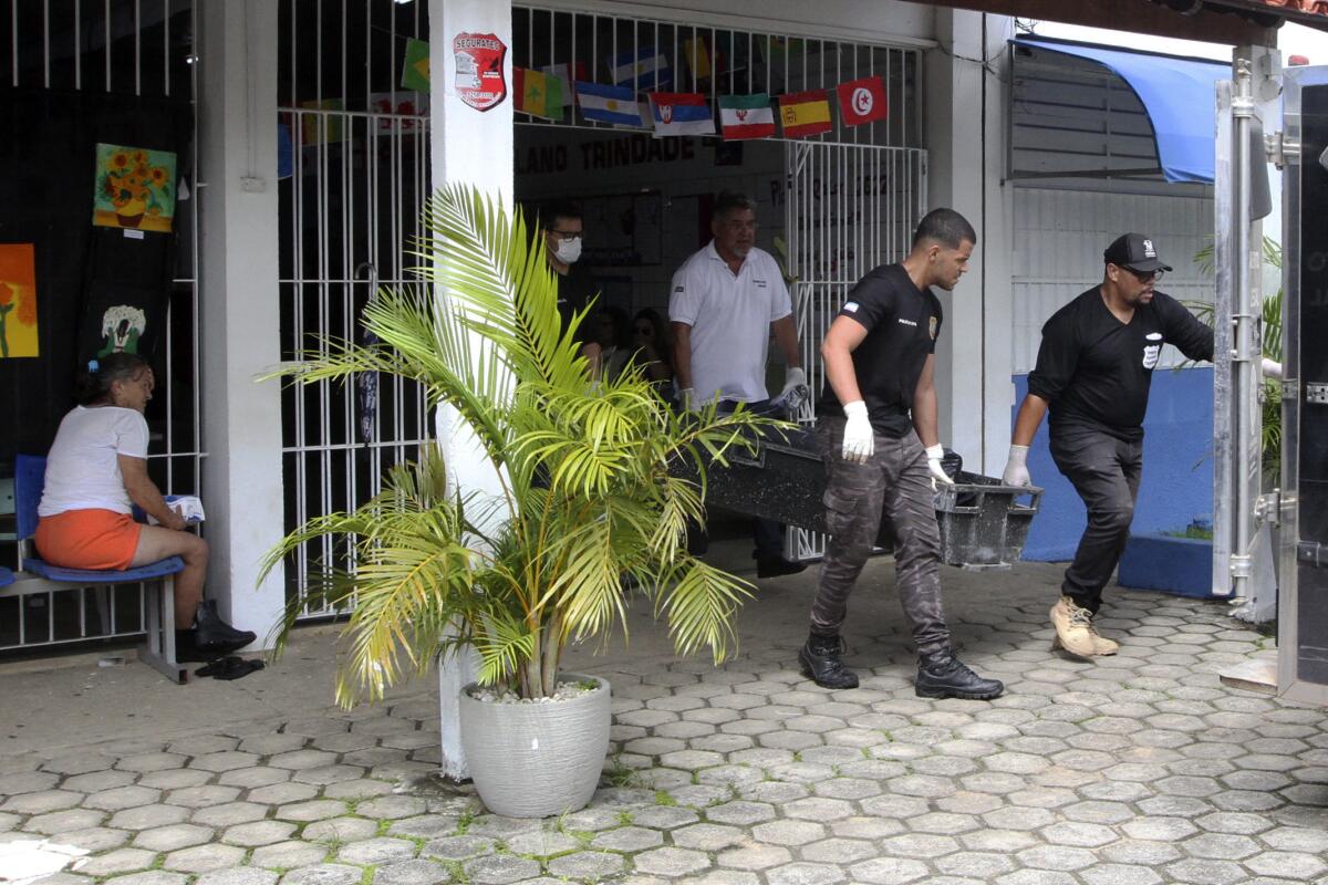 Investigators carry the body of a victim of a shooting at a school in Aracruz, Espirito Santo State, Brazil
