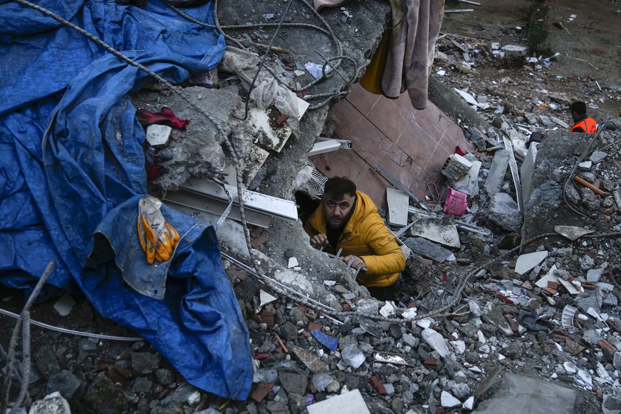 Adana'da Pazartesi günü bir adam yıkılan bir binada insanları arıyor.
