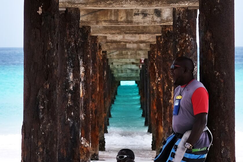 Two locals wait under a jetty for tourists to hire their jet ski on a beach in Bridgetown, Barbados on May 4, 2015. AFP PHOTO/JEWEL SAMAD (Photo credit should read JEWEL SAMAD/AFP via Getty Images)