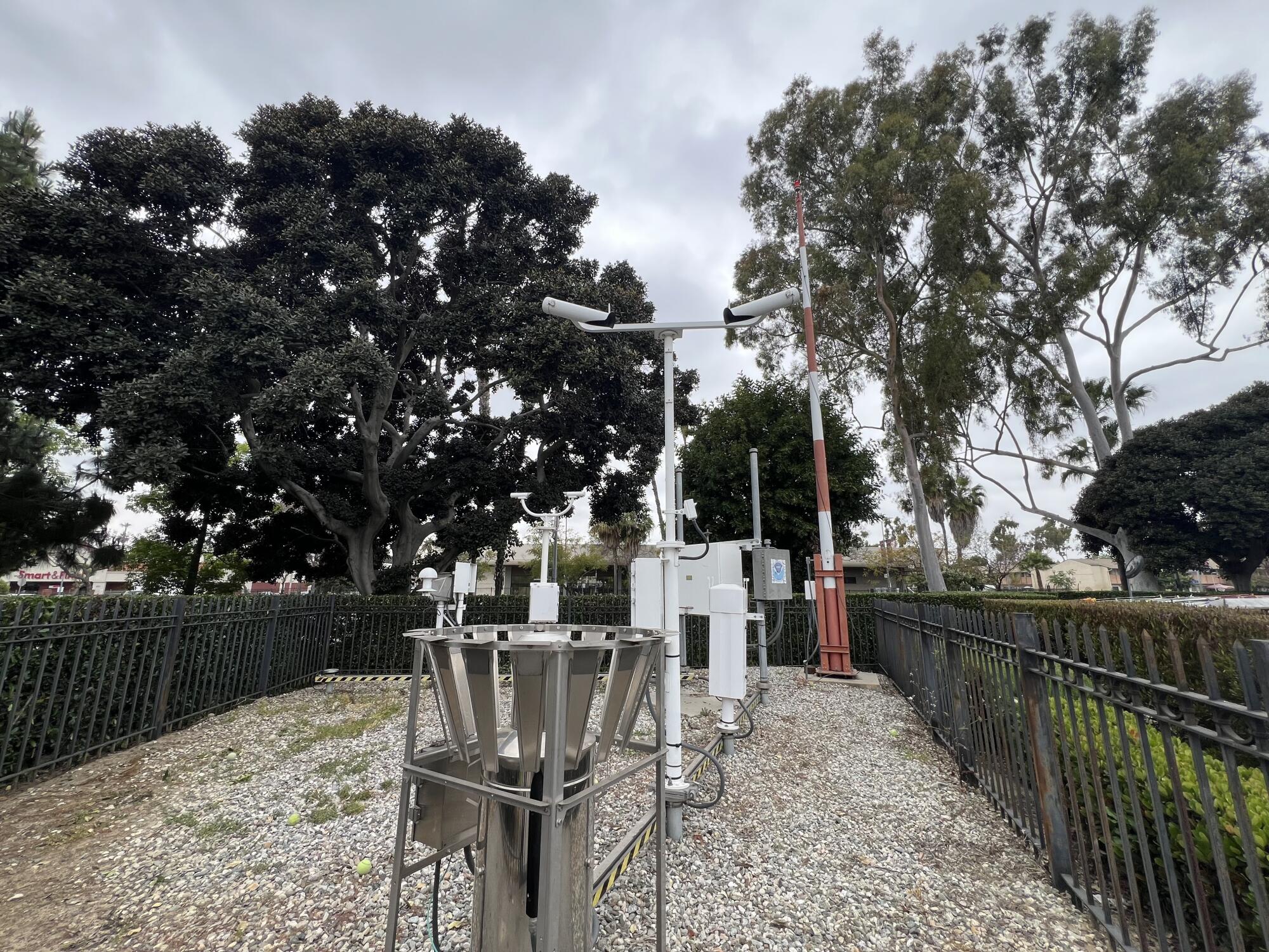 An array of weather observation equipment rises from behind a fence. 