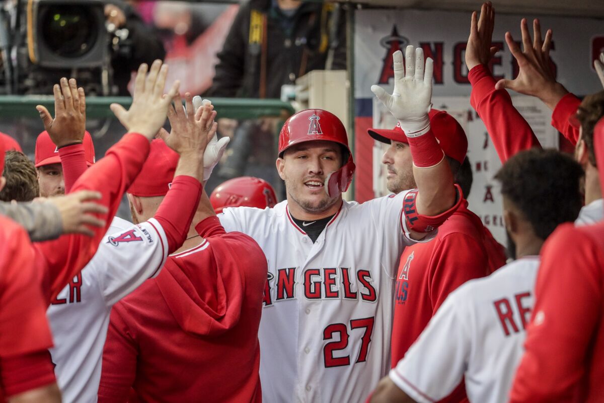 Angels' Mike Trout is greeted by teammates in the dugout during a game.