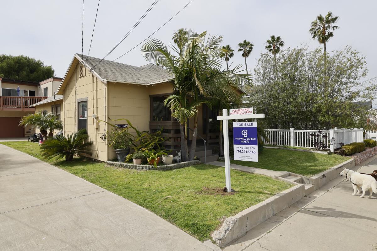 A home for sale sign in front of a house in Huntington Beach.