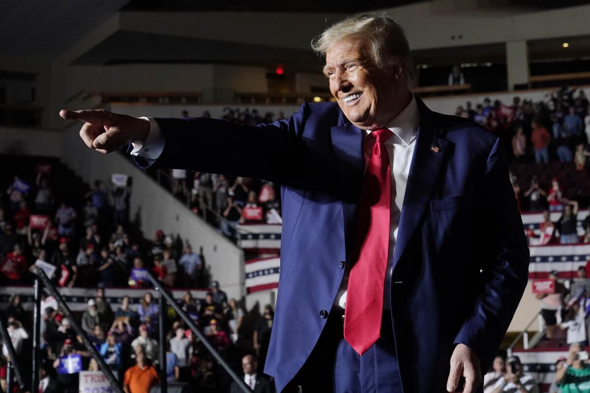 Donald Trump points and smiles to a crowd.