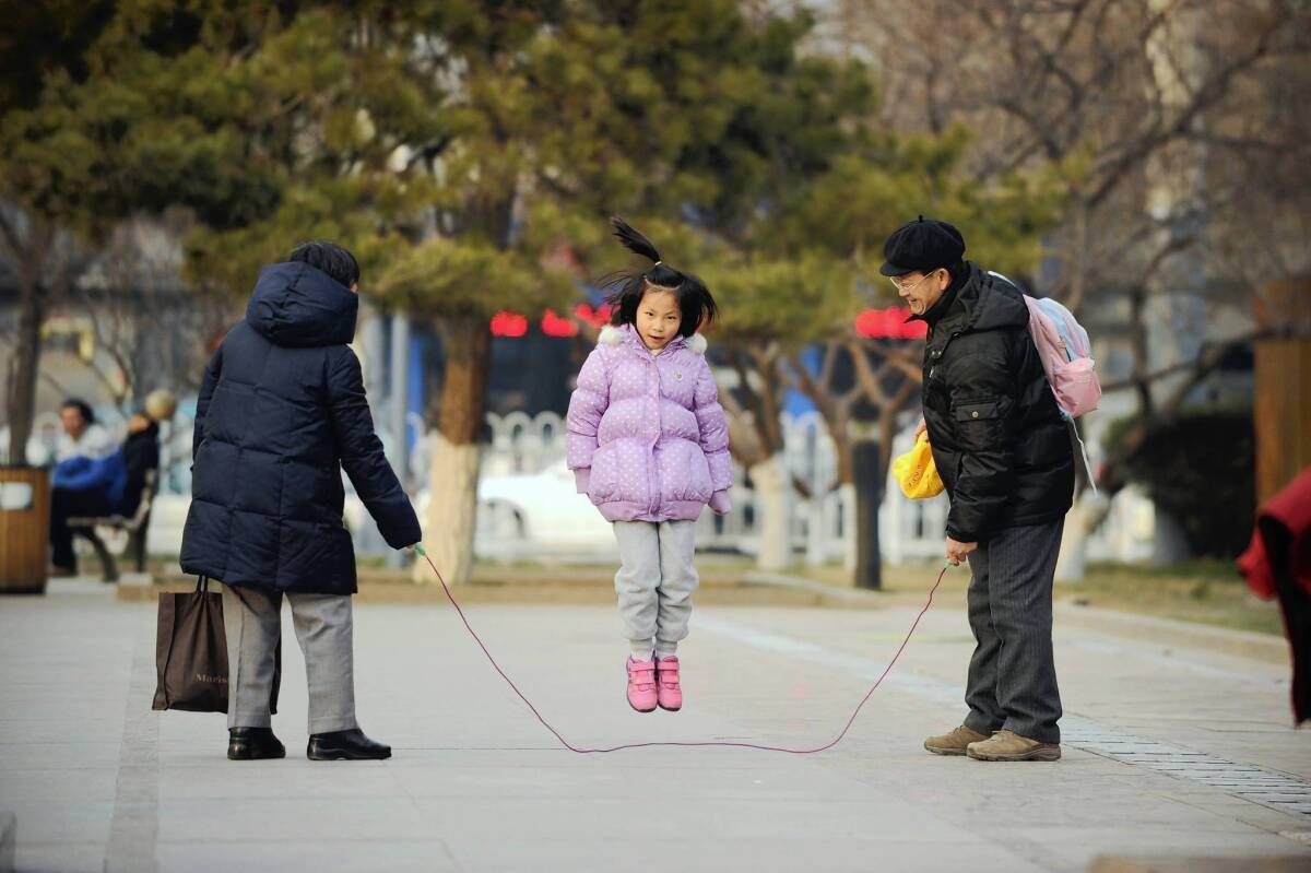 A girl plays jump rope with her family in Beijing. China's leaders announced an easing of the country's deeply unpopular one-child policy.