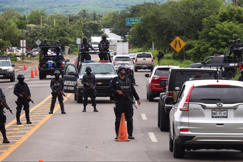 Police officers stand guard at a checkpoint near Nayarit, Mexico, on Wednesday after the kidnapping this week of a son of Sinoloa cartel head Joaquin "El Chapo" Guzman.