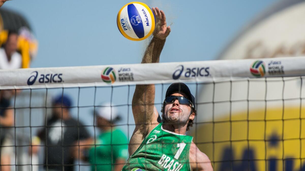 Bruno Schmidt of Brazil spikes the ball at the ASICS beach volleyball tournament in Long Beach on Aug. 23, 2015.