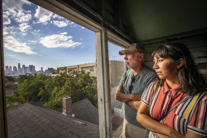 Boyle Heights, CA - September 22: Alex Contreras, and his daughter, Alex Contreras, an activist against highway expansion in Los Angeles, look at the sight of where his childhood home used to be near the 101 Freeway in Boyle Heights. They were looking out an attic window overlooking the sight of where the house Alex grew up in in Boyle Heights was torn down and replaced with an apartment complex through eminent domain. The land to reportedly needed to support a light rail project near the 101 Freeway and across the street from Mariachi Plaza in Boyle Heights. Photo taken on Wednesday, Sept. 22, 2021. Contreras' parents' home in Downey could be threatened by the proposed expansion of the I-5 and I-605. Contreras' great-grandparents had the 101 Freeway built across the street from their home in Boyle Heights. Contreras' grandparents had their home, also in Boyle Heights, taken for a transportation project via eminent domain. Generations of Contreras' family has been affected by highway construction. I'm going to be the Contreras that says, 'No, this is not going to happen. Not under my watch,'" they said. "I've had too many generations suffer. I'm not going to let any more suffer after me." (Allen J. Schaben / Los Angeles Times)