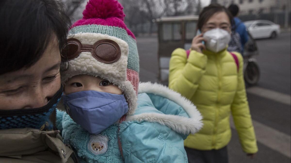 Pedestrians wear masks against the smog outside a hospital in Beijing. A new study outlines the myriad ways climate change is already worsening human health and causing premature deaths.