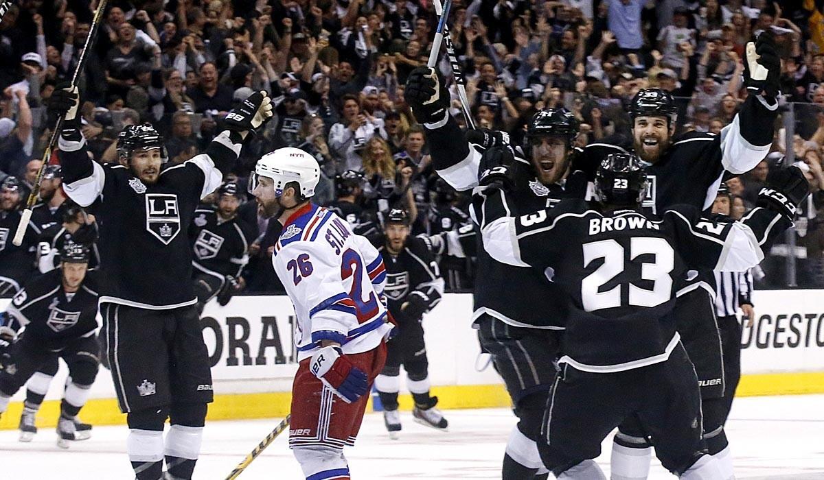 Rangers right wing Martin St. Louis skates off the ice as Kings players swarm captain Dustin Brown (23) after his game-winning goal in the second overtime of Game 2.