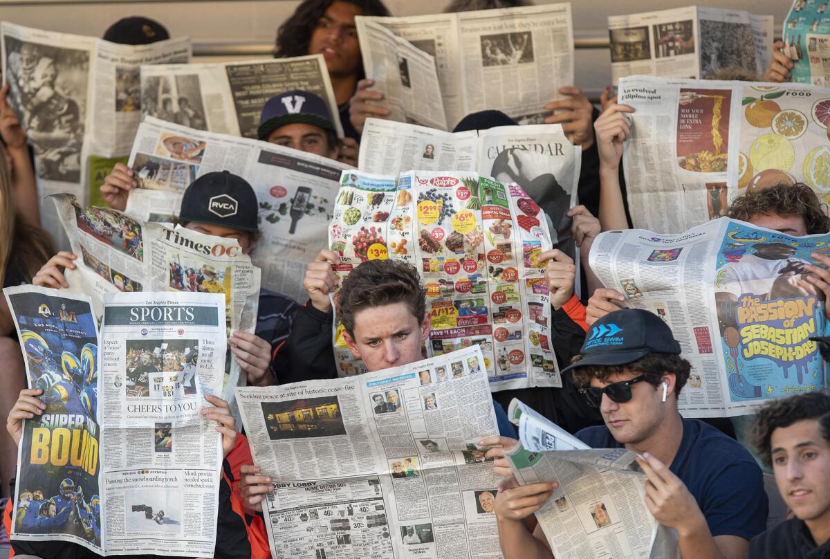 Huntington Beach students hold up newspapers to block out Santa Barbara on Wednesday.