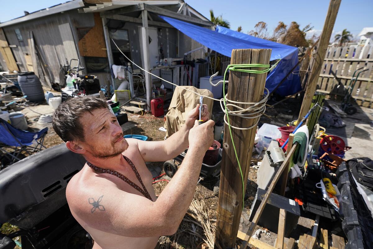 A man puts up a tarp next to his mobile home.