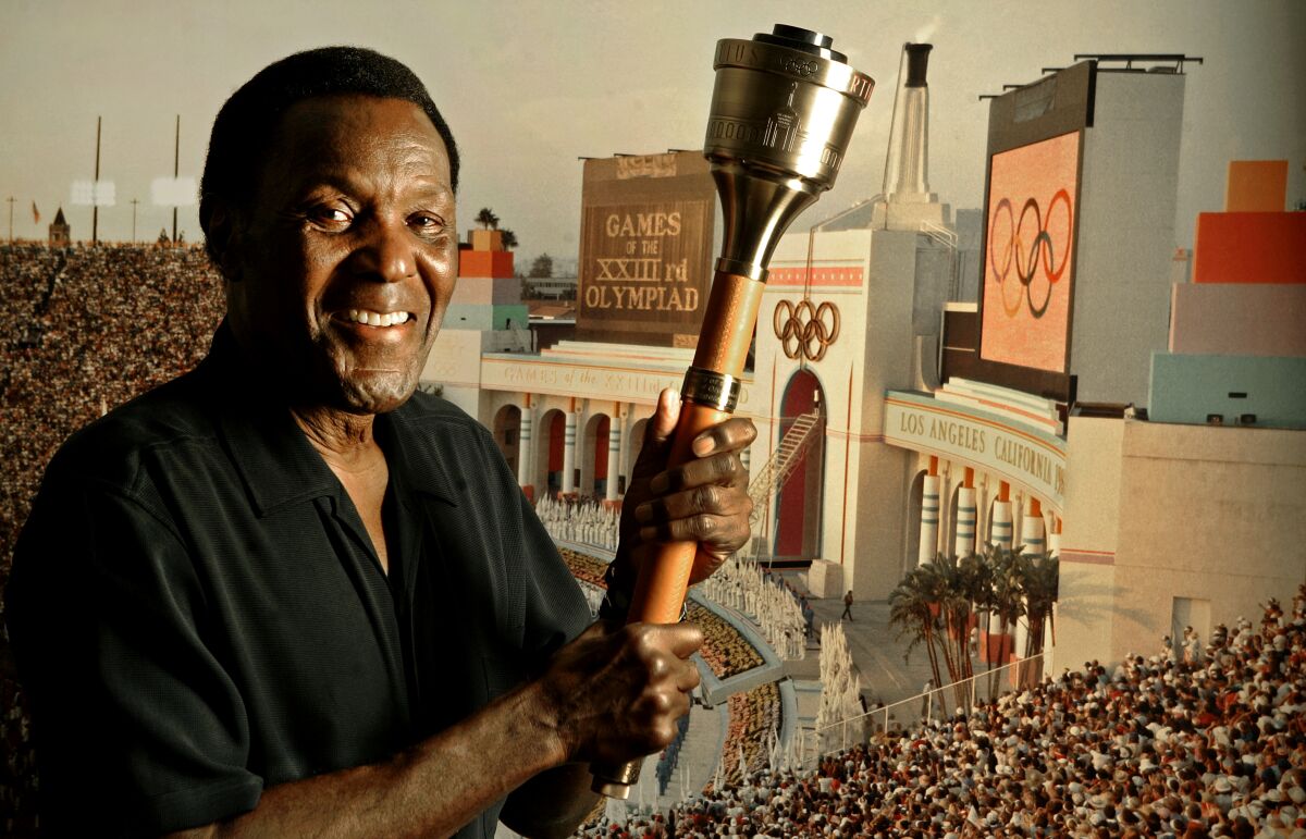 Rafer Johnson holds the cauldron that he used to light the Olympic flame 
