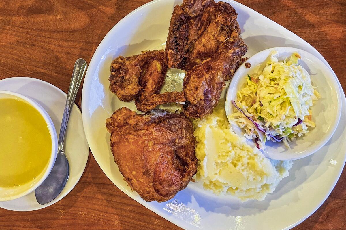 A plate of fried chicken with mashed potatoes and coleslaw.