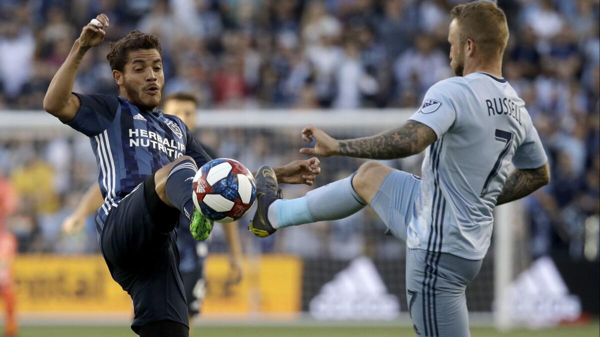 Sporting Kansas City forward Johnny Russell (7) and Galaxy midfielder Jonathan dos Santos compete for the ball during the first half of on Wednesday in Kansas City, Kan.