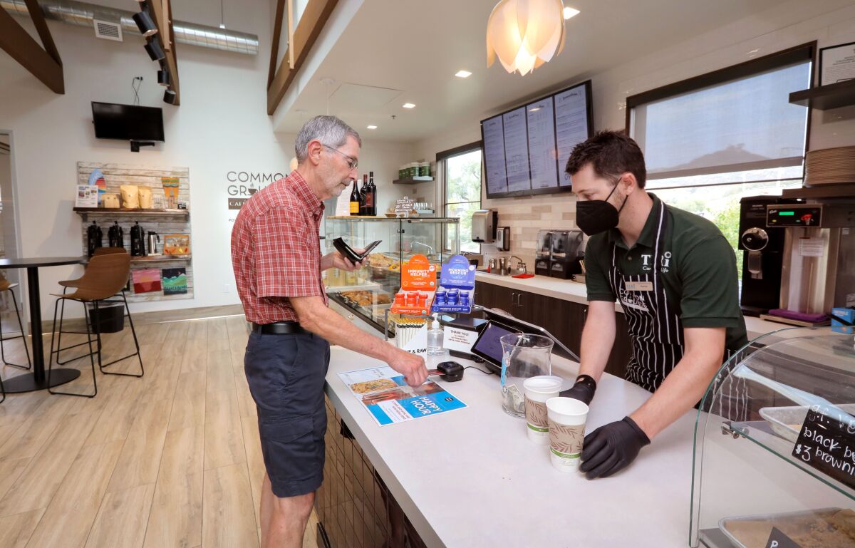 Rod Koelewyn buys coffee from Patrick Nuzum at Common Grounds Cafe & Coffee Bar.