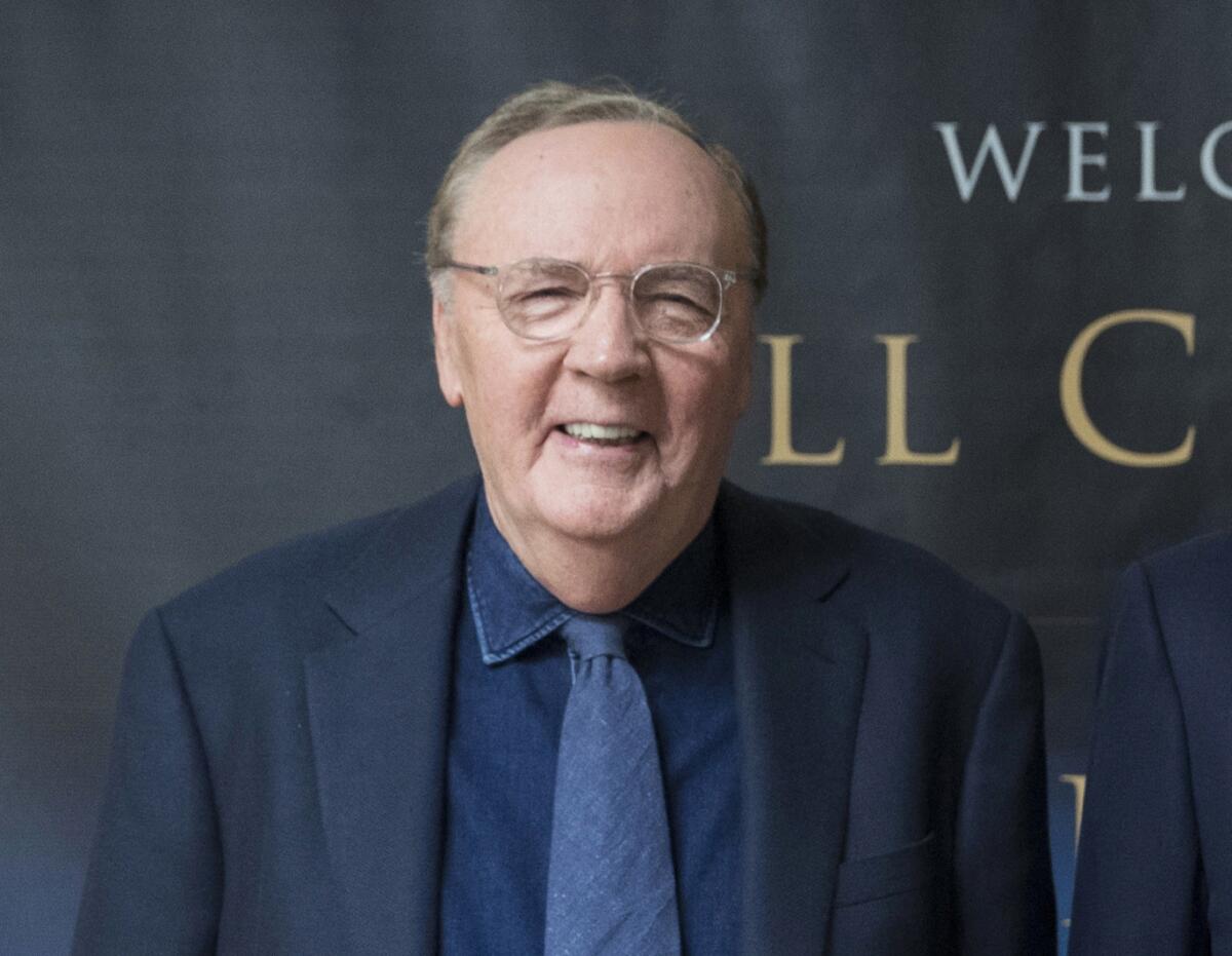 A smiling older man wearing clear-rimmed glasses and a dark suit