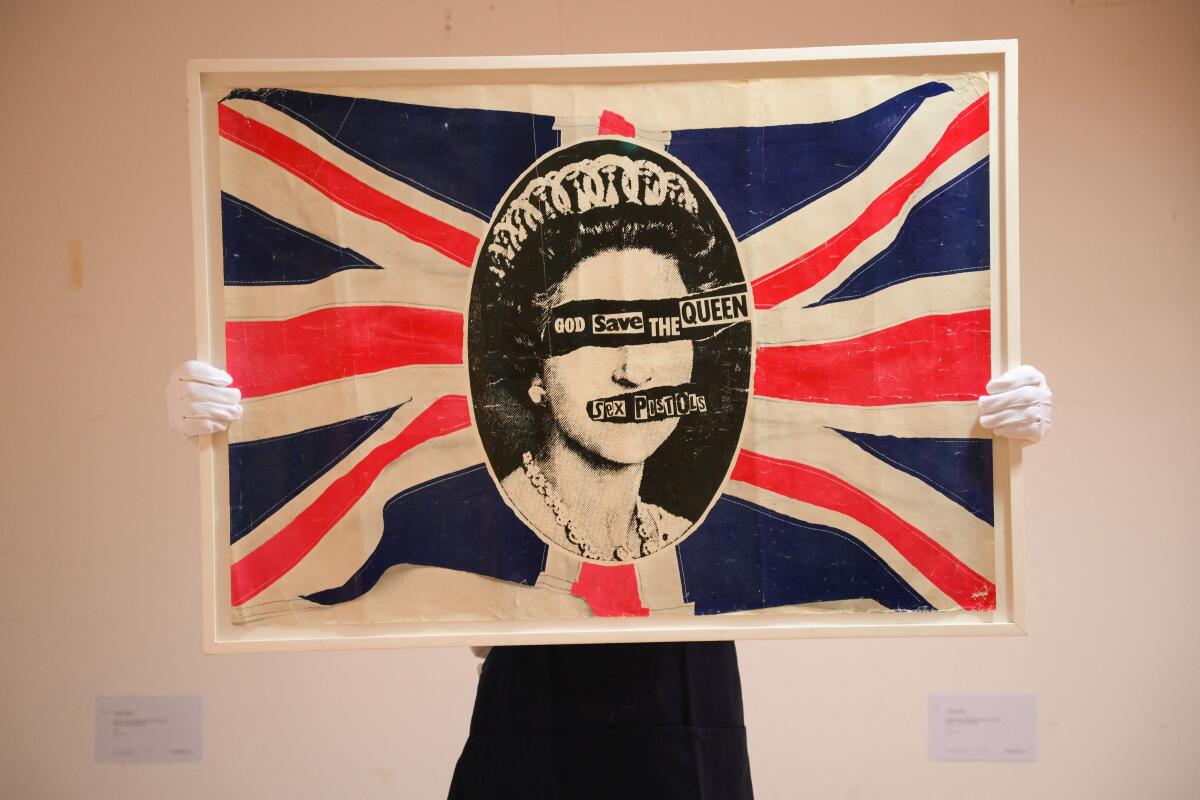 A poster of the British flag with Queen Elizabeth's face at the center covered with the words God Save the Queen.