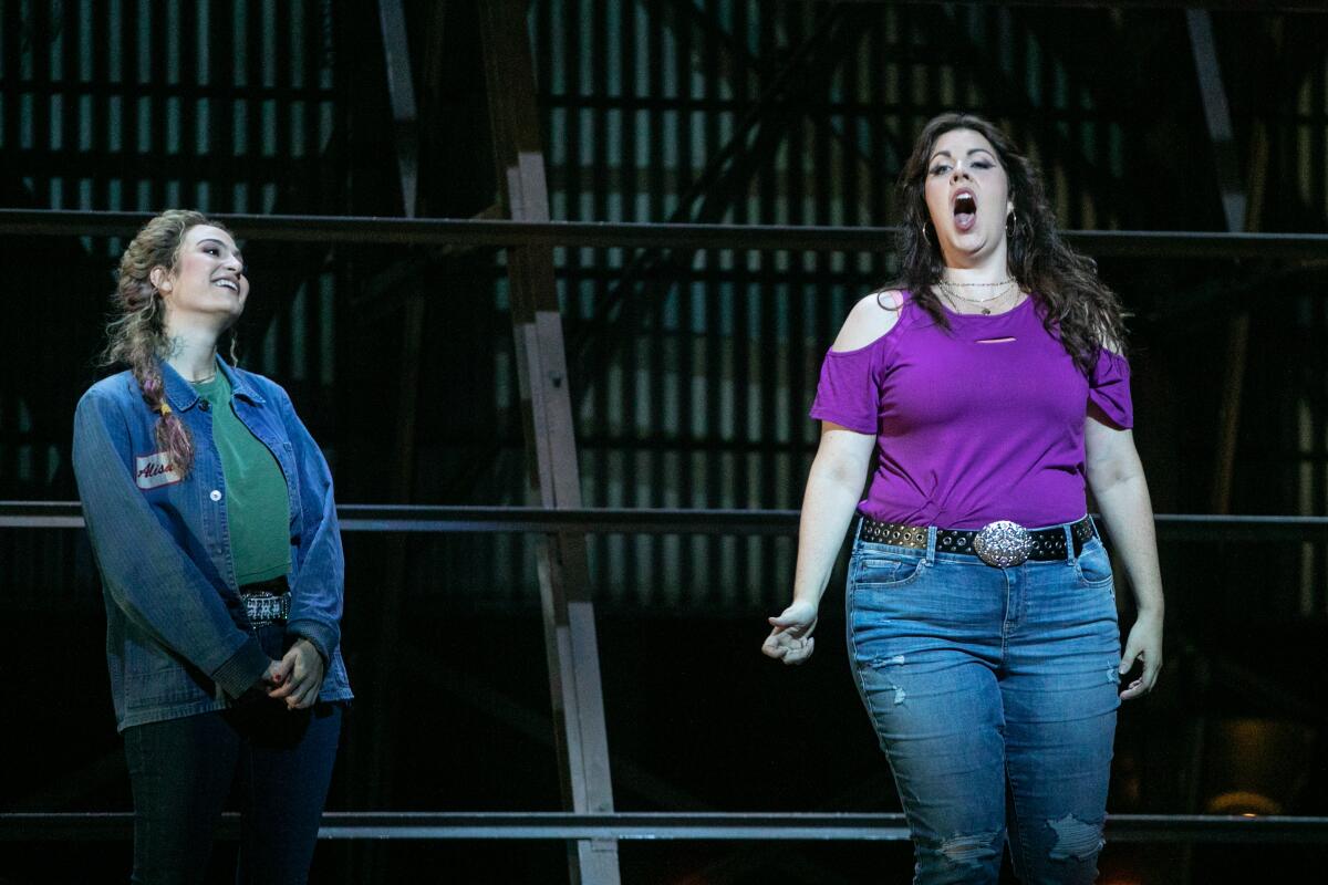 Amanda Woodbury sings onstage while Madeleine Lyon looks on with a smile in  L.A. Opera's "Lucia di Lammermoor"