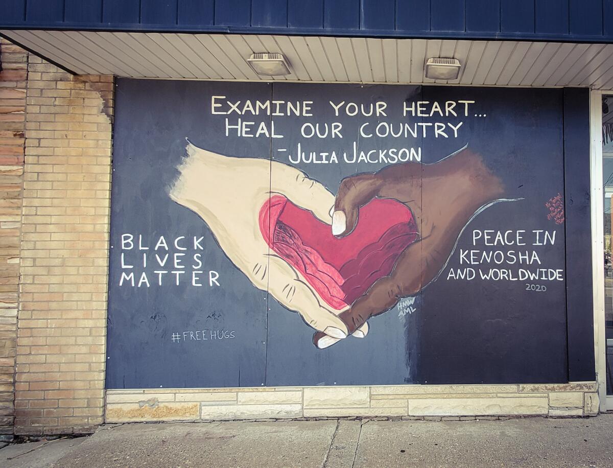 A mural of a white hand and Black hand forming a heart, with the words Examine your heart, heal our country