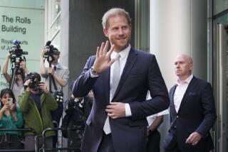 Prince Harry smiles and waves in suit as photographers take his picture on his way out of a British courthouse