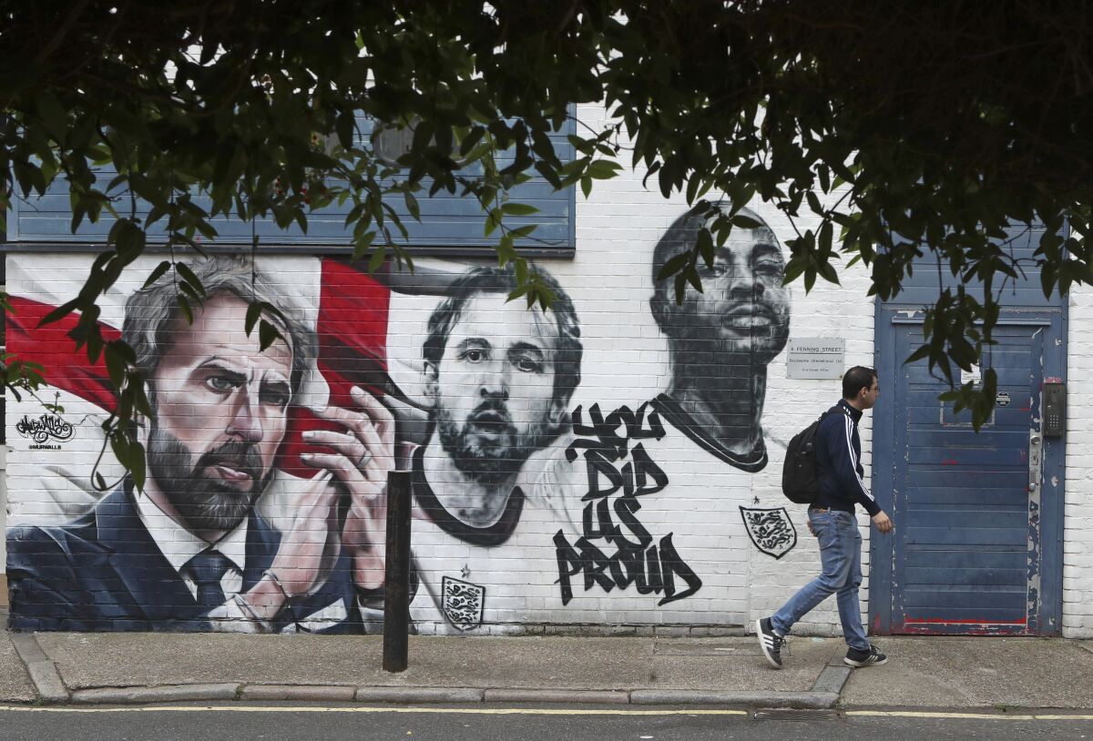 A man walks past a mural depicting England's manager Gareth Southgate, captain Harry Kane and Raheem Sterling, from left, painted on a wall near Vinegar Yard in south London, Wednesday July 14, 2021. England lost the Euro 2020 soccer championship final match to Italy on Sunday July 11. (AP Photo/Tony Hicks)