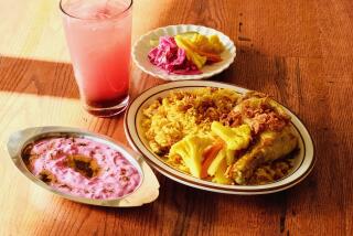 A horizontal photo of chicken with turmeric rice, pickles, and a sour cherry limeade at Azizam restaurant in Silver Lake.