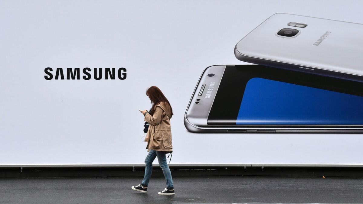 A woman checks her phone while passing by a billboard advertising a Samsung smartphone Oct. 11 in Berlin. The smartphone maker announced a total halt of production of the Galaxy Note 7 on Tuesday.