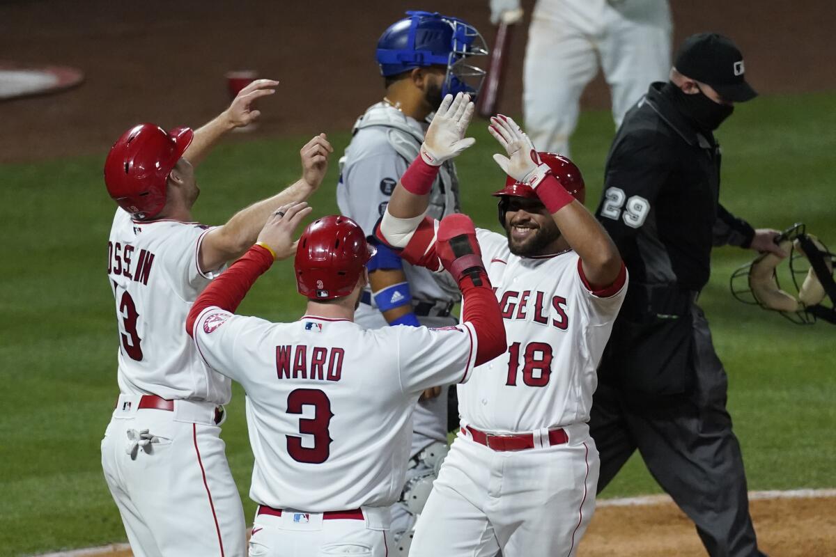 The Angels' Jose Rojas (18) celebrates his three-run homer with Phil Gosselin, left, and Taylor Ward on May 8, 2021.